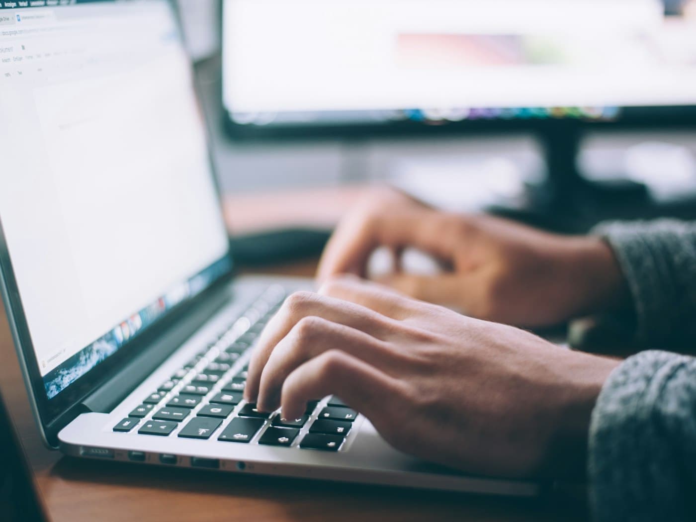 Hands typing on a laptop in a workspace
